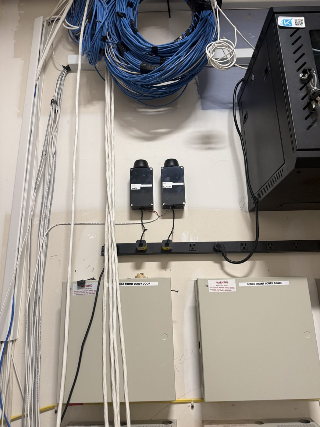 Wired devices and enclosures on a utility room wall during an access control repair